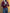Stylish man wearing a burgundy V-neck button-front knit cardigan with gray trousers.